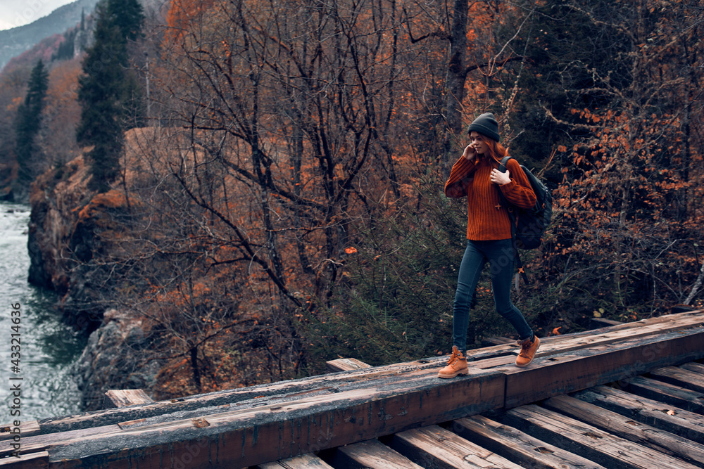 woman stands on a bridge over a river in the mountains Autumn forest travel