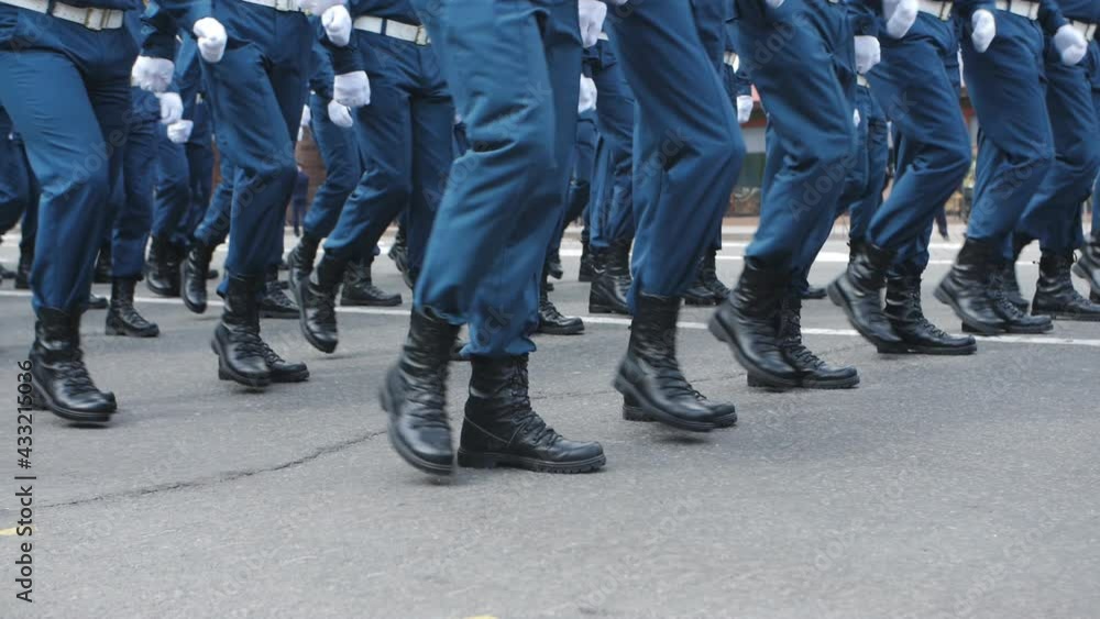 Soldiers in blue uniforms and black boots march through the city streets during the parade. Soldiers in blue uniforms and black boots march through the city streets during the parade.