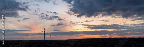 Sunset over windmills. Innovative energy creator for electric power production. Panoramic landscape.