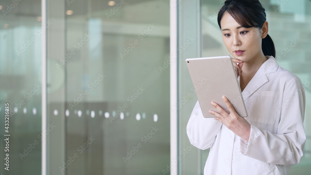 タブレットを見る白衣の女性 医師 科学者 タブレットを見る白衣の女性 医師 科学者