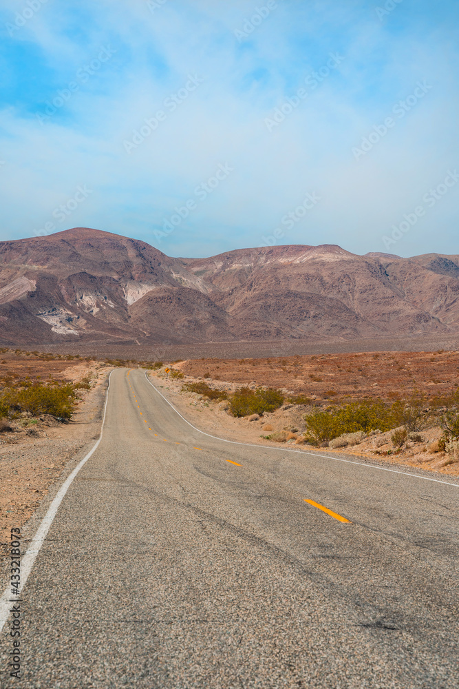 Desert scenic road in Death Valley with mountain backdrop, California, USA. Amazing panorama of desert