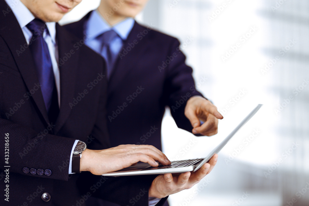 Business people discussing a presentation at meeting, standing in a modern office. Unknown businessman with a colleague search for some information at the laptop, lawyers at negotiation. Teamwork and Business people discussing a presentation at meeting, standing in a modern office. Unknown businessman with a colleague search for some information at the laptop, lawyers at negotiation. Teamwork and