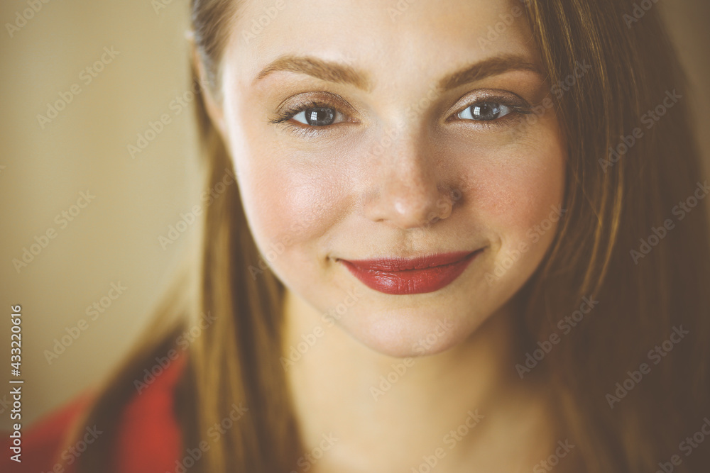 Head shot of a smart confident smiling millennial european woman standing with folded arms at home. Attractive young teenager student girl freelancer looking at camera, dressed in red Head shot of a smart confident smiling millennial european woman standing with folded arms at home. Attractive young teenager student girl freelancer looking at camera, dressed in red