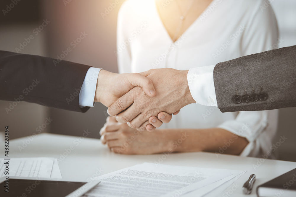 Business people shaking hands finishing contract signing in sunny office, close-up. Handshake and marketing Business people shaking hands finishing contract signing in sunny office, close-up. Handshake and marketing