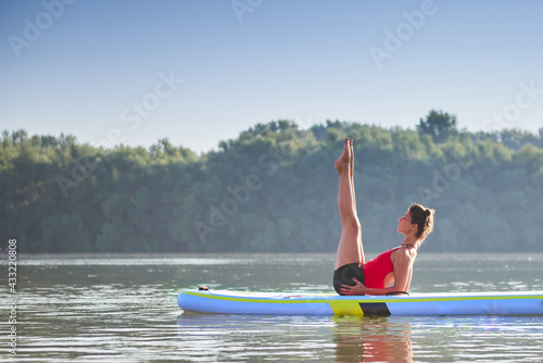 Woman meditating and practising yoga during sunrise in paddle board © Marko