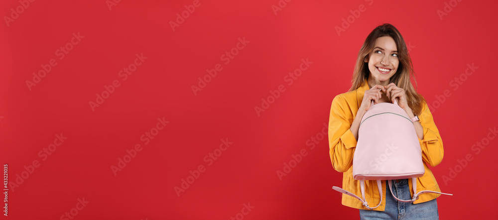 Happy woman with backpack on red background. Space for text Happy woman with backpack on red background. Space for text