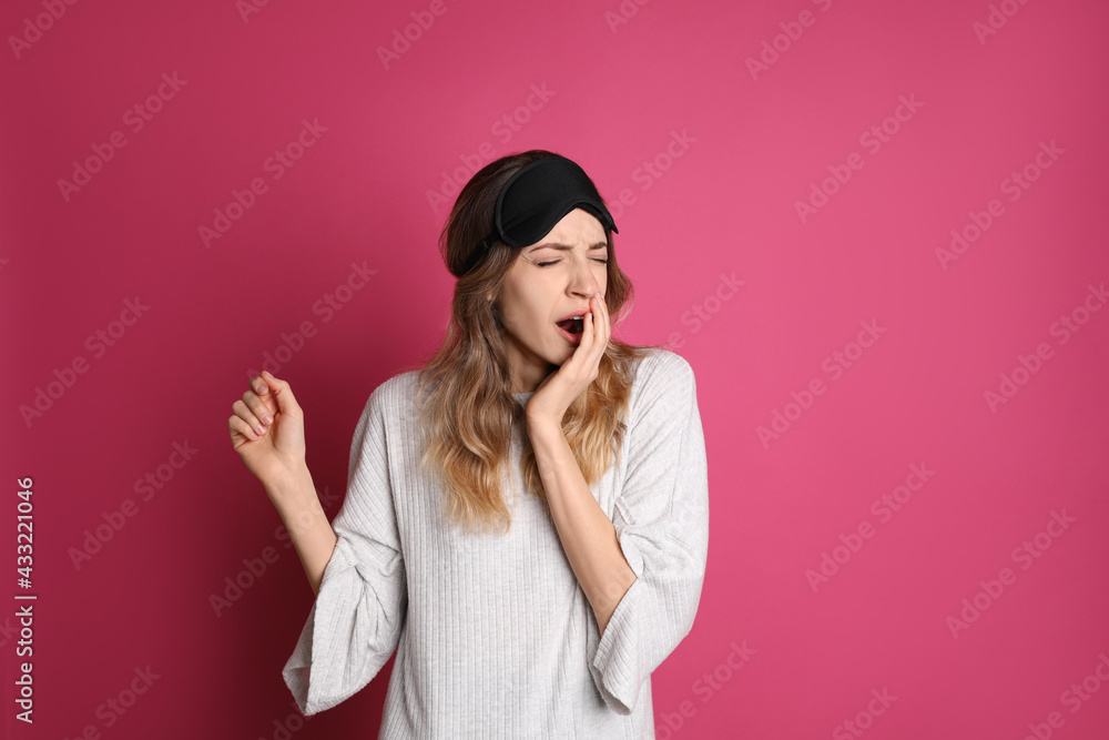 Young tired woman with sleeping mask yawning on pink background Young tired woman with sleeping mask yawning on pink background