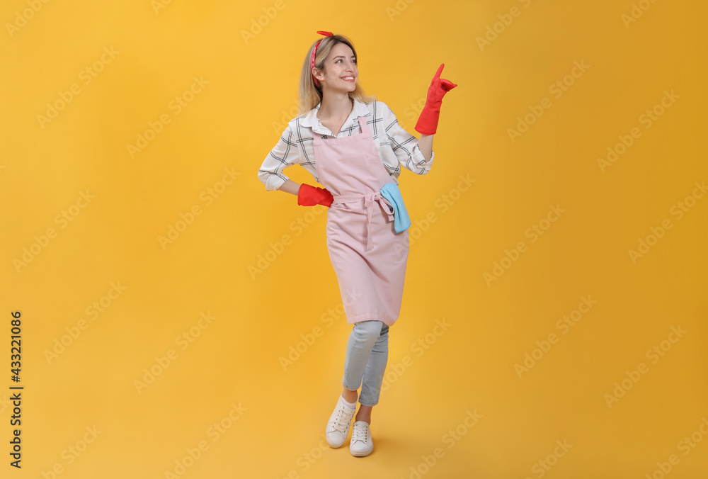Young housewife in gloves on yellow background Young housewife in gloves on yellow background