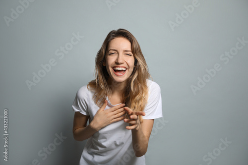Cheerful young woman laughing on grey background