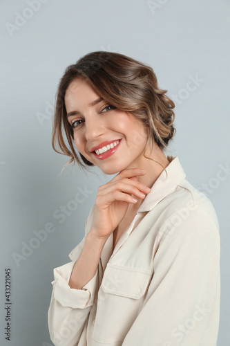 Young woman with beautiful hairstyle on light grey background
