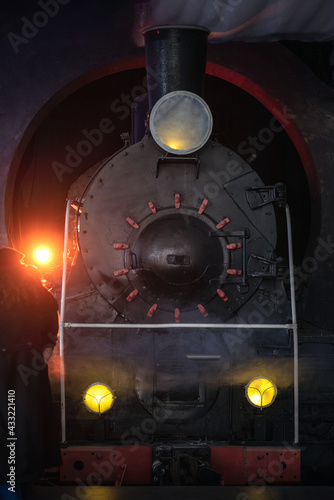 An old steam locomotive in the dark with lighted lanterns.