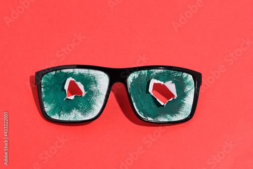 Summer concept of summer vacation and fun.Sunglasses decorated with two white flowers. Isolated on red background.