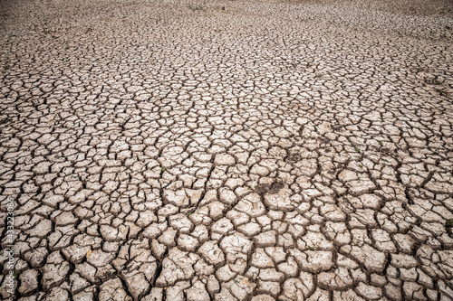 Dry soil cracked in an arid environment without water. Copy space background, texture