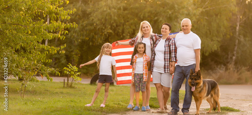 big family are walking walking american flags. Front view, american patriots on the park meadow. © Angelov