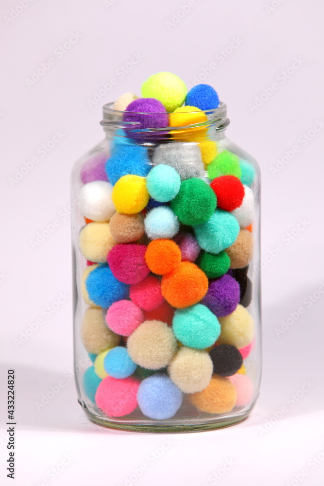 Colorful pompom in glass bottle on white background Colorful pompom in glass bottle on white background