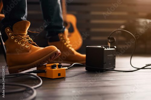 Guitarist foot wearing boots using guitar pedal