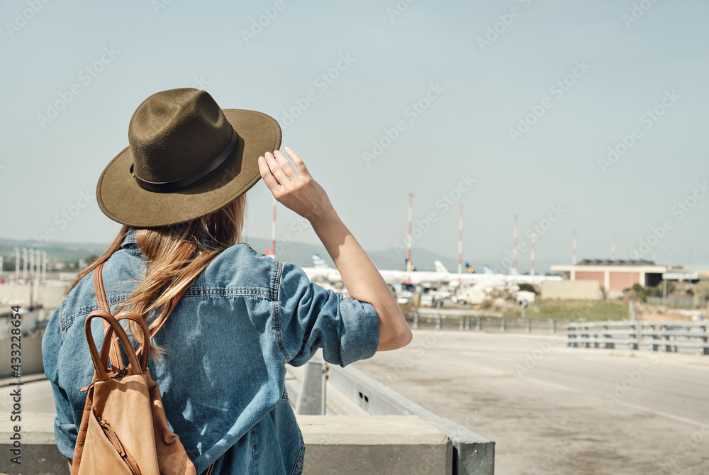 Girl in hat with backpack traveling in the airport