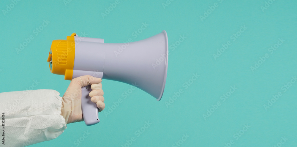 Hand hold megaphone and wear PPE suit on mint green or Tiffany Blue background. Hand hold megaphone and wear PPE suit on mint green or Tiffany Blue background.