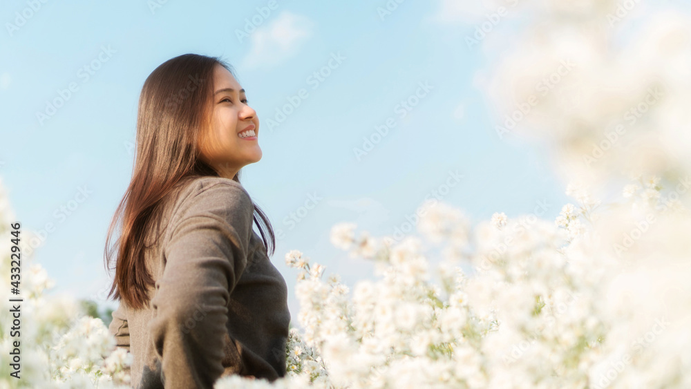 Asian woman stands among a white margaret flower. Asian woman stands among a white margaret flower.