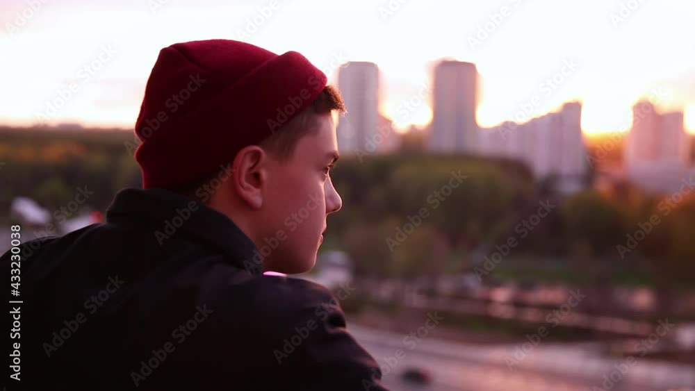 A young man watches from the height of the observation deck the life of the city, thoughtful. Sunset sunlight. A young man watches from the height of the observation deck the life of the city, thoughtful. Sunset sunlight.