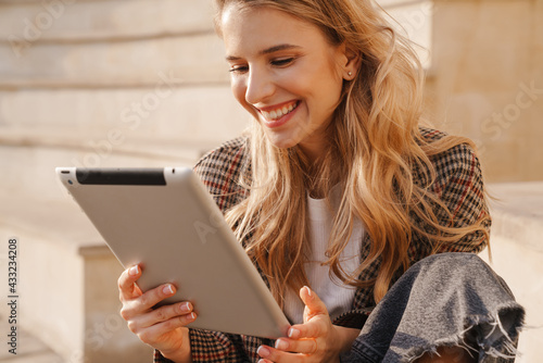 Smiling young blonde woman holding tablet