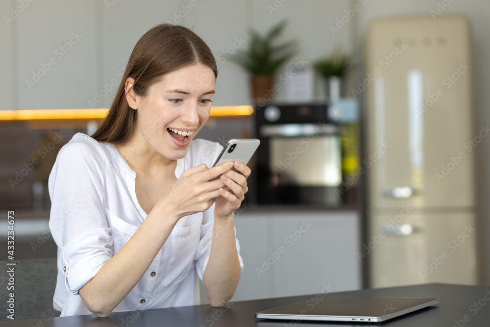 Excited young woman with smartphone reading unexpected good news on cellphone. Happy female stunned surprised by online lottery win Excited young woman with smartphone reading unexpected good news on cellphone. Happy female stunned surprised by online lottery win