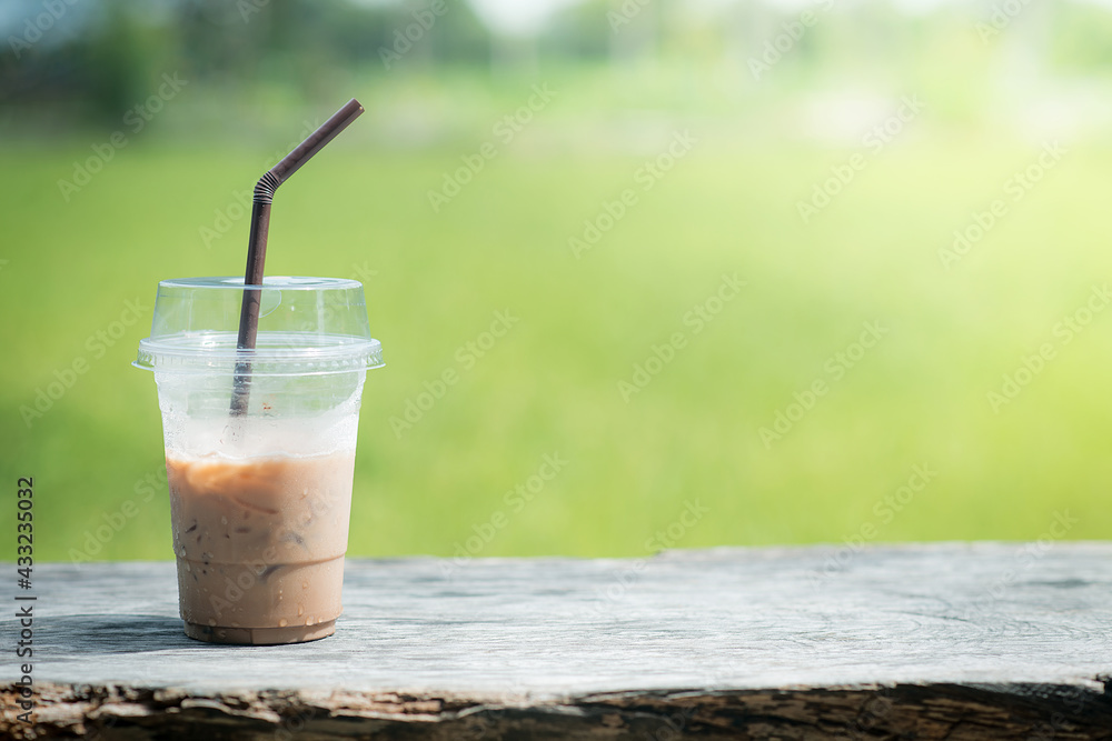 Iced coffee in a transparent plastic mug straw with a lid on a table on a green background Iced coffee in a transparent plastic mug straw with a lid on a table on a green background