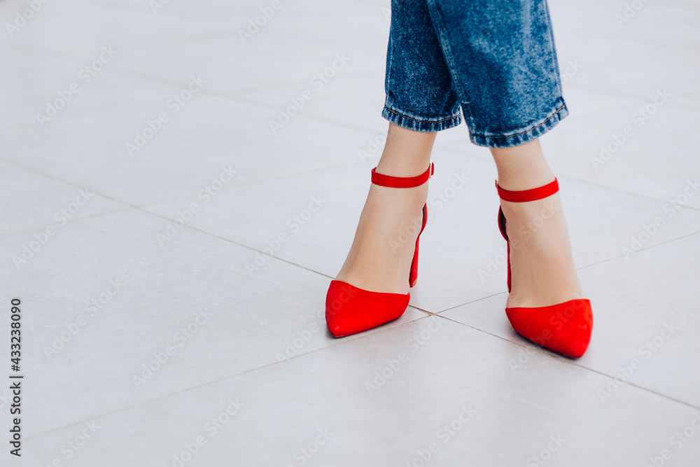 Small business owner office worker woman standing outside building legs red shoes high heels. Female successful executive girl walking on the street. Copy space. Fashion concept, blue jeans Small business owner office worker woman standing outside building legs red shoes high heels. Female successful executive girl walking on the street. Copy space. Fashion concept, blue jeans