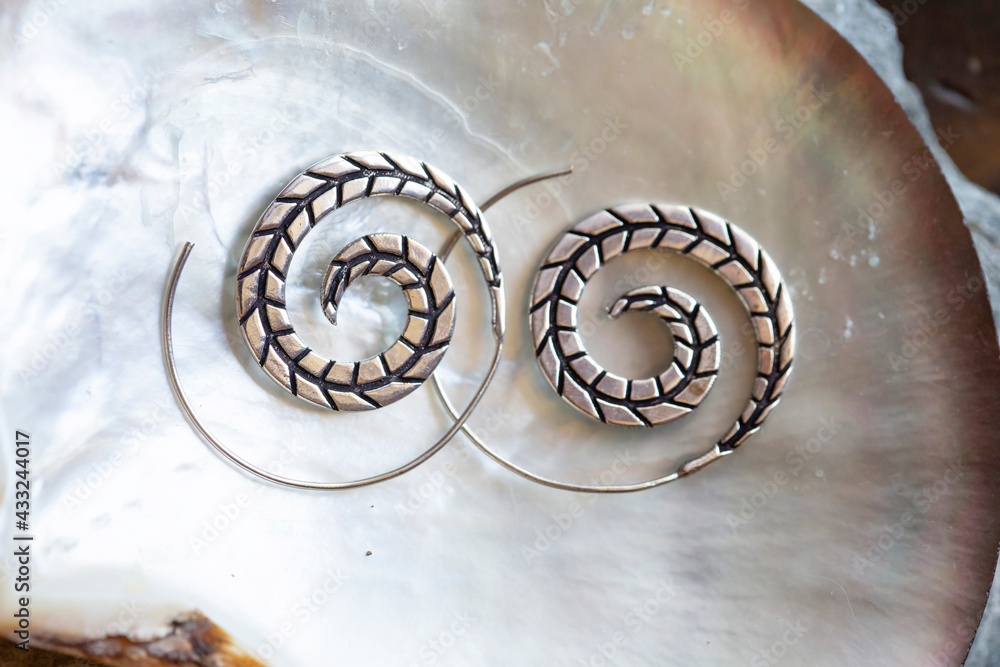 Silver metal decorative oriental spirale design earrings on natural neutral background Silver metal decorative oriental spirale design earrings on natural neutral background