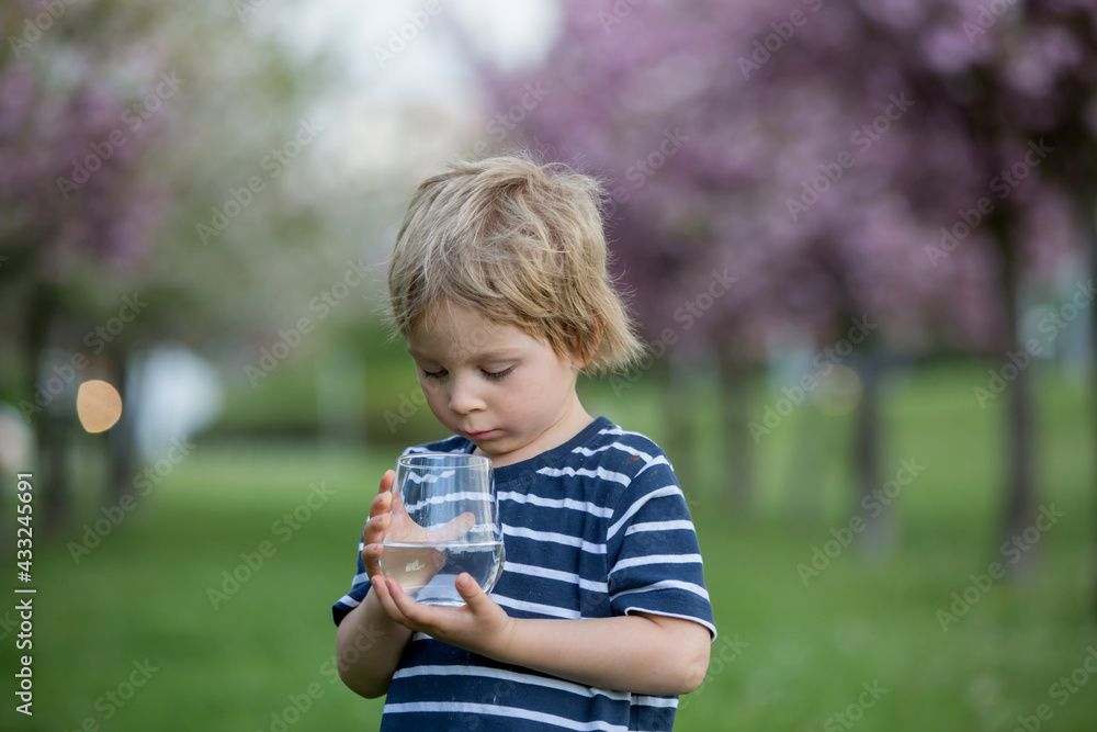 Beautiful blond child, boy, drinking water in the park on a hot day Beautiful blond child, boy, drinking water in the park on a hot day