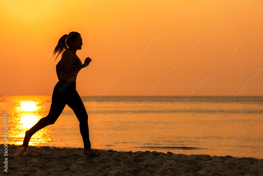 Silhouette athletic woman jogging and relax and freedom on sand beach. People running and workout in sunset background. Lifestyle and Healthy Concept.