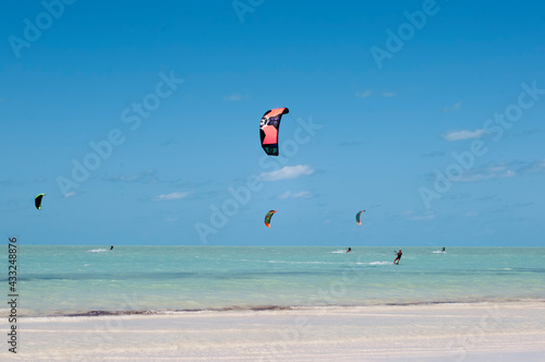 Kite surfing from the tropical beach of Holbox Island in Mexico, during low tide. In the background the Caribbean ocean and the blue sky 