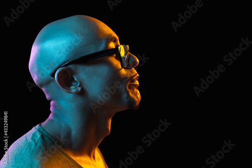 African-american young man's portrait on dark studio background in neon. Concept of human emotions, facial expression, youth, sales, ad.