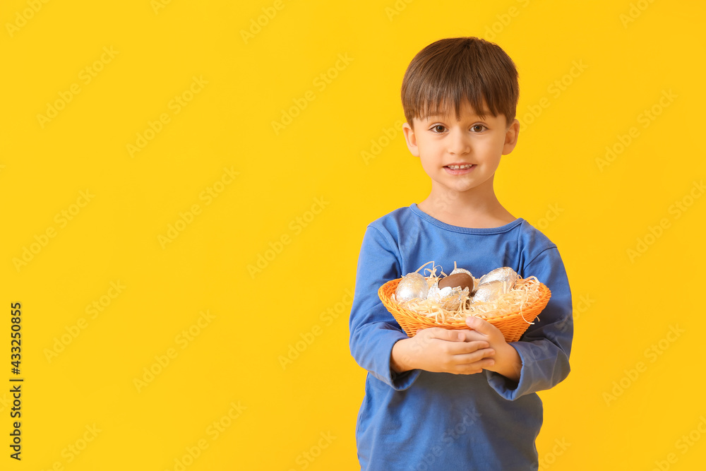 Cute little boy with basket of chocolate Easter eggs on color background Cute little boy with basket of chocolate Easter eggs on color background