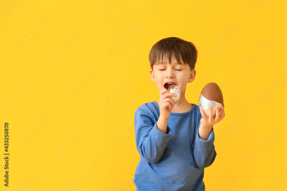 Cute little boy with chocolate Easter eggs on color background Cute little boy with chocolate Easter eggs on color background