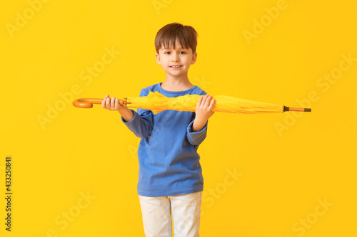 Cute little boy with umbrella on color background