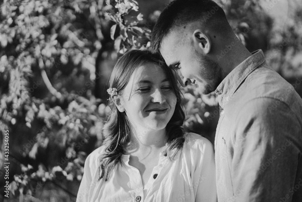 Black and white photo. Young beautiful couple hugging in the spring garden. Black and white photo. Young beautiful couple hugging in the spring garden.