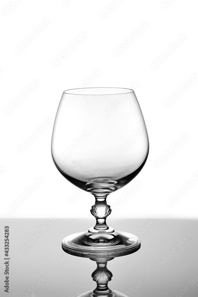 Empty cognac glass. Shooting glass in the light. Cut-off pattern and volume Empty cognac glass. Shooting glass in the light. Cut-off pattern and volume