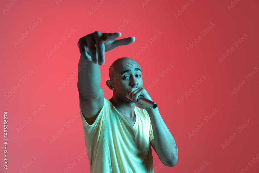 African-american young man's portrait on red studio background in neon. Concept of human emotions, facial expression, youth, sales, ad. African-american young man's portrait on red studio background in neon. Concept of human emotions, facial expression, youth, sales, ad.