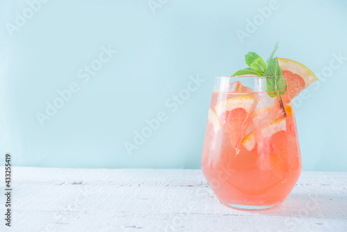 One glass with summer cold drink lemonade with grapefruit pieces, ice and mint copy space