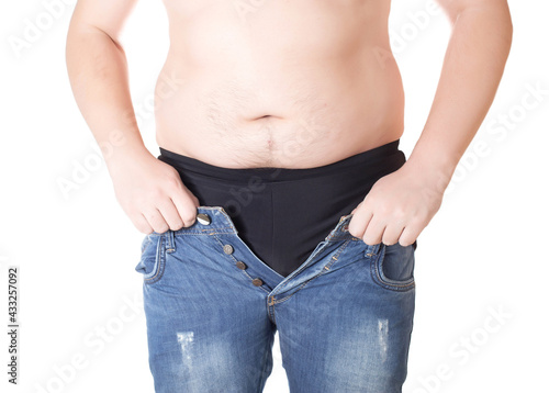 An obese man tries to put on tight little shorts on a white background. Overweight concept, wrong lifestyle © HENADZY