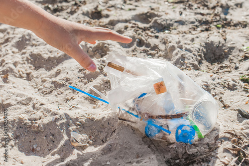 The girl's hand cleans up the garbage on the beach. Pollution and Ecology Concept