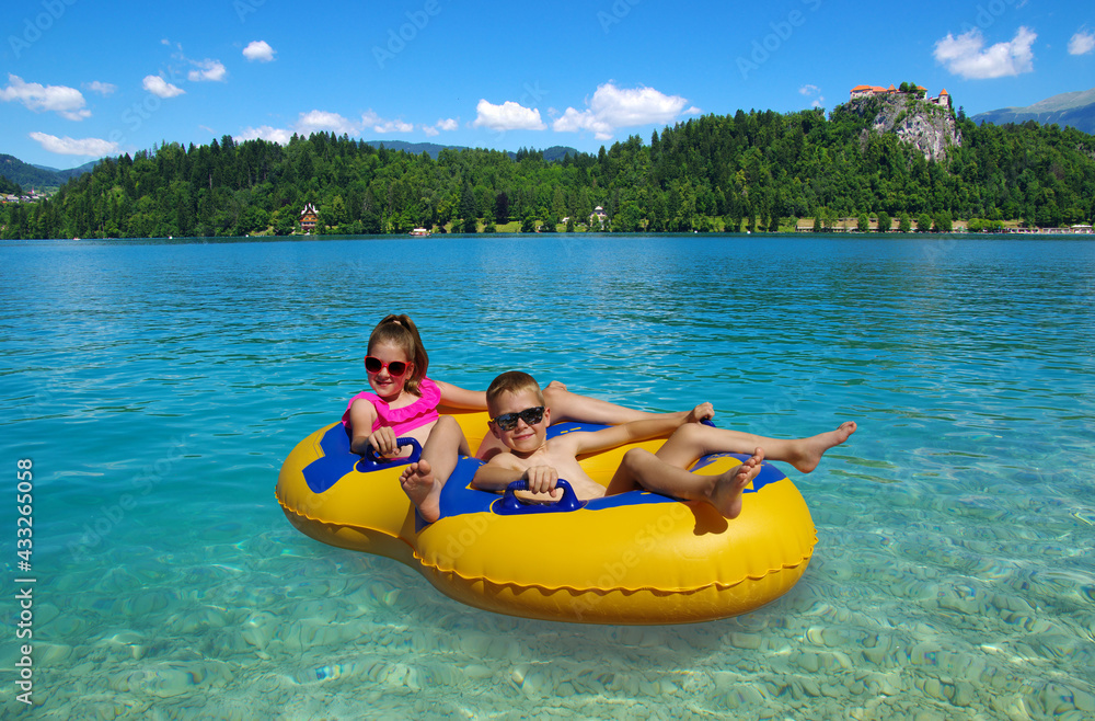 Boy and girl on inflatable float in lake. Little children floating in ...