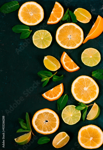 Background, sliced lime and lemon, citrus fruit, with mint, on a dark green table, top view, no people,