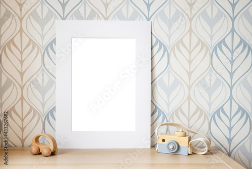White frame mock up for photo, print art, text or lettering, with kids room decorations and toys. Blank frame on wooden table.