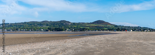 Panoramic view of Portmarnock beach, County Dublin, Ireland. Vivid colors, Howth green fields in the background. Person during sport activities, running outdoor.