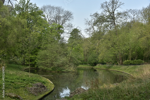Fototapeta Naklejka Na Ścianę i Meble -  L'un des étangs entouré de végétation luxuriante sous l'ombre d'un nuages au parc Josaphat à Schaerbeek 