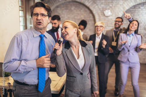 Business people having a karaoke party at the office, singing, dancing and having fun while taking a break from a bussy work day