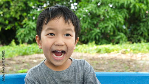 Asian cute child boy laughing with mouth open wide, whitening teeth. Happy kid with wow mouth, surprised face enjoying in funny shot in relaxing day. Concept of healthy lifestyle, happy expression.