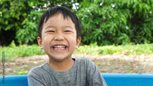 Asian cute child boy smiling and laughing with whitening teeth in nature background.Happy kid in happy moment and enjoying in funny shot in relaxing day. Concept of healthy lifestyle,happy expression.